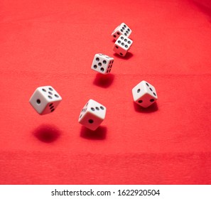 Hand Throwing Dice, Hoping For The Best Odds. Six Dice On Red Background