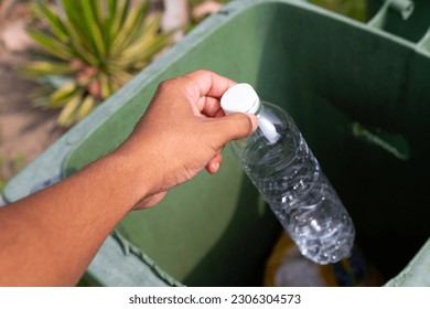 Hand throwing empty plastic bottle into recycle garbage trash.