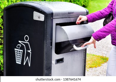  Hand throwing garbage in empty recycling bin.A modern smart trash can on the street. Collection of waste in Europe for subsequent disposal.Concept of environmental protection