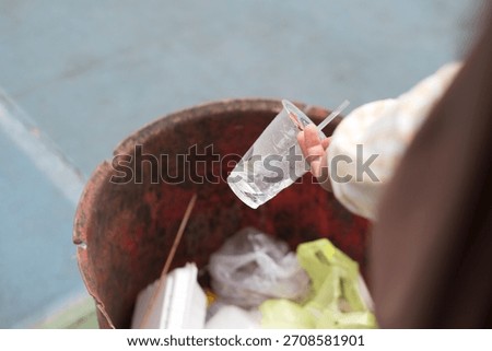 Hand Throwing Plastic Cup Into Trash Bin Close-Up