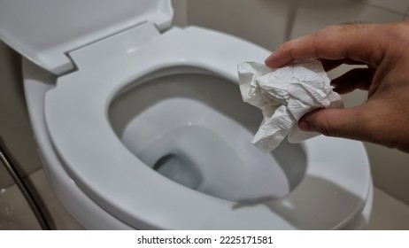 Hand Throwing Tissue Paper Directly In The Toilet Bowl.
