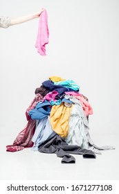 hand throws clothes into a pile with used clothes. Pile of used clothes on a light background. Second hand for recycling