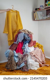 Hand throws clothes into a pile with used clothes. The concept of sustainable fashion. Pile of used clothes on a light background. Second hand for recycling