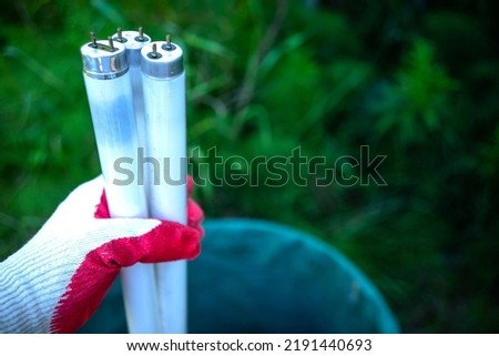The hand throws the fluorescent lamps into the trash. Recycling of old office lamps. Throw away the fluorescent lamps.
