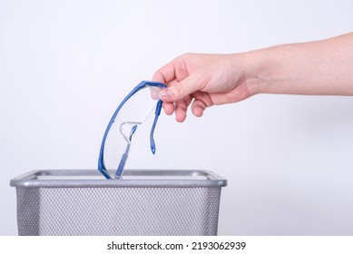 A Hand Throws Out Medical Glasses Against A Gray Background. The Concept Of Medical Waste Disposal.