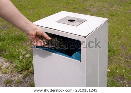 Hand Throws out Smartphone, Throwing Electronic Device into Street Trash Can, Throwed Away Smartphone, Dangerous Garbage Concept, Blurred Background