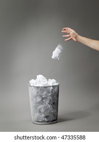 Hand Tossing A Crumpled Paper In Trash Can.