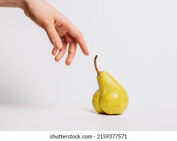 A hand touches an unusual pear-shaped remake of the renaissance and the creation of adam. The concept of cultivation of new varieties of fruits and vegetables, human impact on agriculture and nature