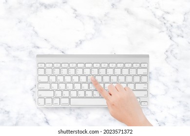 Hand touching computer keyboard on marble texture desk with copy space