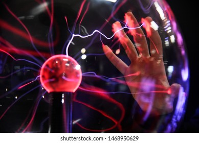 Hand touching with finger electric plasma in glass sphere