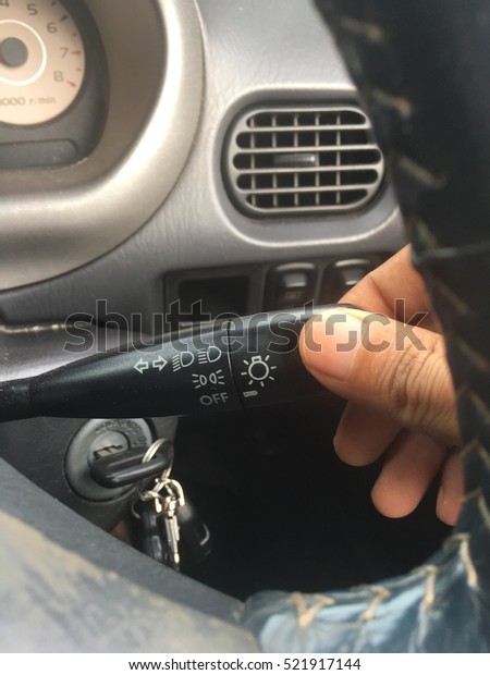 hand touching headlight and left right signal\
controlling stick in car.