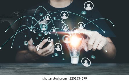 Hand Touching A Light Bulb And Holding Mobile Phone With Icon Management To Describe The Selection Of Leaders And Staff. Enterprise Resource Planning ERP