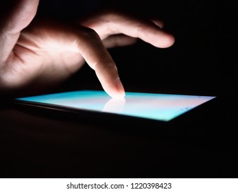 Hand touching on screen of smartphone on dark background.