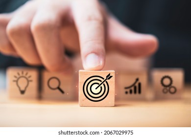 Hand  touching and push target board which printing on wooden cube block on mechanical gear and lightbulb icon  for creative and set up business objective target  goal concept. - Shutterstock ID 2067029975