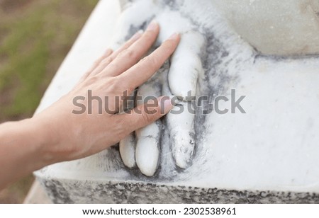 hand touching stone  sculpture's hand. Dating emotionally unavailable partners metaphor. Grieving breakup or love loss. Relationship trauma.