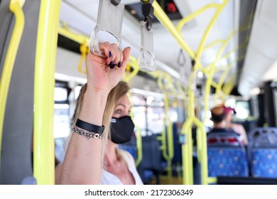 Hand of tourist passenger in protective mask holding handrails in bus. Safety in public transport concept