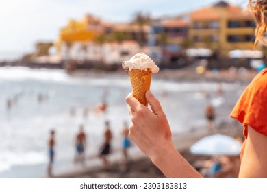 Hand of a tourist woman smiling with a hat eating an ice cream on the beach of Valle Gran Rey in La Gomera, Canary Islands - Powered by Shutterstock