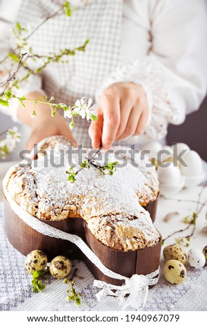 In hand Traditional Italian desserts for Easter - Easter dove . Festive pastries with almonds and sugar icing on a light background and flowering branches, Easter decor and eggs. vertical 