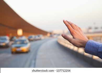 Hand Of Traveler Hailing A Taxi Outside Of The Airport