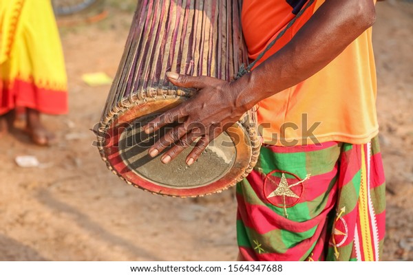 Hand of a tribal man in close up playing a\
traditional musical instrument known as the \