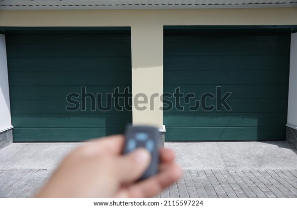 The hand tries to open the garage\
door with the remote control. Garage with two gates,\
double.