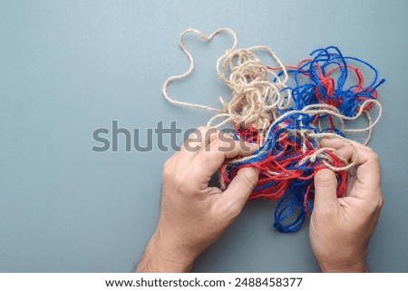 Hand trying to solve the problem of tangled jute ropes, confused circumstance, and psychotherapy concept