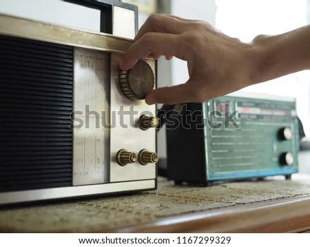 Hand tuning vintage radio with blurred background of antique transistor radio. Once upon a time concept, Nostalgic memories theme. (close up, selective focus, space for text, article layout design)
