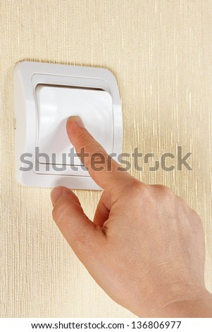 Hand turn off the light switch on the wall