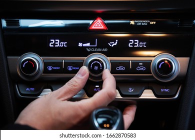 Hand turn on air conditioner dial button in a korean modern luxury car.