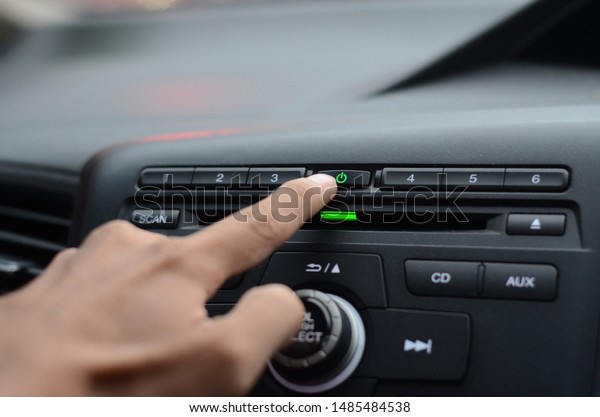 hand turn on the radio in the car.Hand driver\
touching the screen and turning on car radio system,Button on\
dashboard in car panel