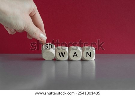 Hand turned a dice and form the expression SD WAN. Symbol for Software defined Wide Area Networking. Beautiful red background. Copy space.