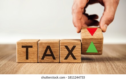 Hand is turning a cube and changes the direction of an arrow symbolizing that the taxes is going down or vice versa. Business concept.
