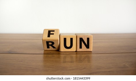 Hand is turning a cube and changes the word Fun to Run. Beautiful wooden table, white  background. Lifestyle concept, copy space.