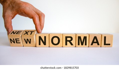 Hand is turning cubes and changes the words 'new normal' to 'next normal'. Covid-19 postpandemic concept. Beautiful white background, copy space.