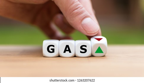 Hand Is Turning A Dice And Changes The Direction Of An Arrow Symbolizing That The Price For Gas Is Changing The Trend And Goes Up Instead Of Down (or Vice Versa)