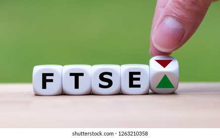 Hand is turning a dice and changes the direction of an arrow symbolizing that the FTSE 100 Index is changing the trend and goes up instead of down (or vice versa)