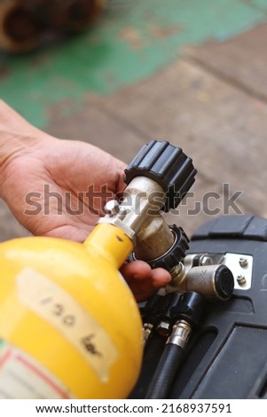 a hand is turning the valve in the breathing apparatus cylinder while checking the fire prevention or fire fighting system on ship