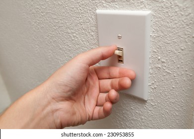 Hand turning wall light switch off