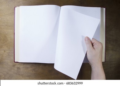 Hand turns the blank sheet of books on a wooden table - Powered by Shutterstock