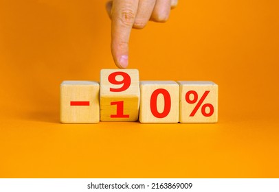 Hand turns a cube and changes the expression '-10 percent' to '-90 percent'. Beautiful orange background, copy space. Business concept.