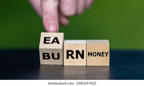 Hand turns cube and changes the expression 'burn money' to 'earn money'.