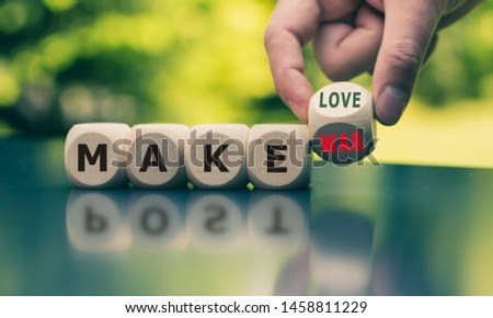 Hand turns a cube and changes the expression "make war" to "make love".