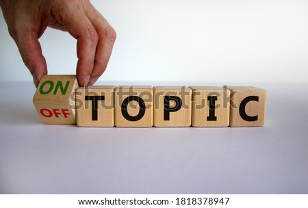 Hand turns a cube and changes the expression 'off topic' to 'on topic'. Beautiful white background. Business concept. Copy space.