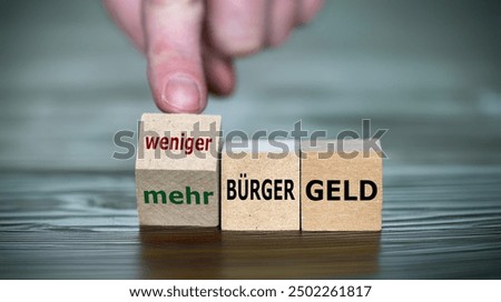 Hand turns cube and changes the expression 'more citizen money' to 'less citizen money'. ('mehr Buergergeld' and 'weniger Buergergeld' in German)