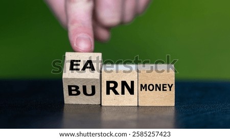 Hand turns cube and changes the expression 'burn money' to 'earn money'.