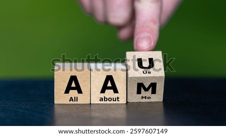 Hand turns cube and changes the expression AAM (all about me) to AAU (all about us).