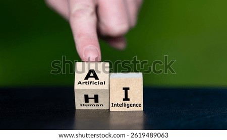 Hand turns cube and changes the expression HI (human intelligence) to AI (artificial intelligence).