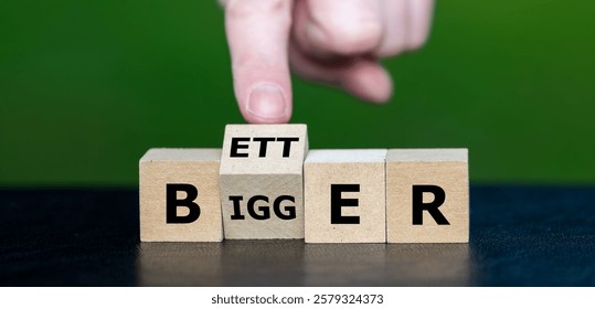 Hand turns cube and changes the word 'bigger' to 'better'.   