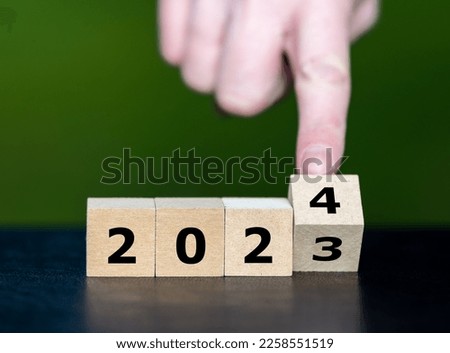 Hand turns cube and changes the year 2023 to year 2024.
