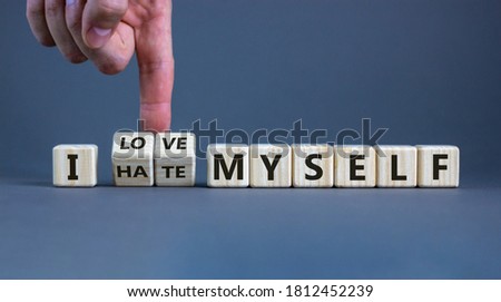 Hand turns cubes and changes the expression 'I hate myself' to 'I love myself'. Beautiful grey background, copy space. Concept.